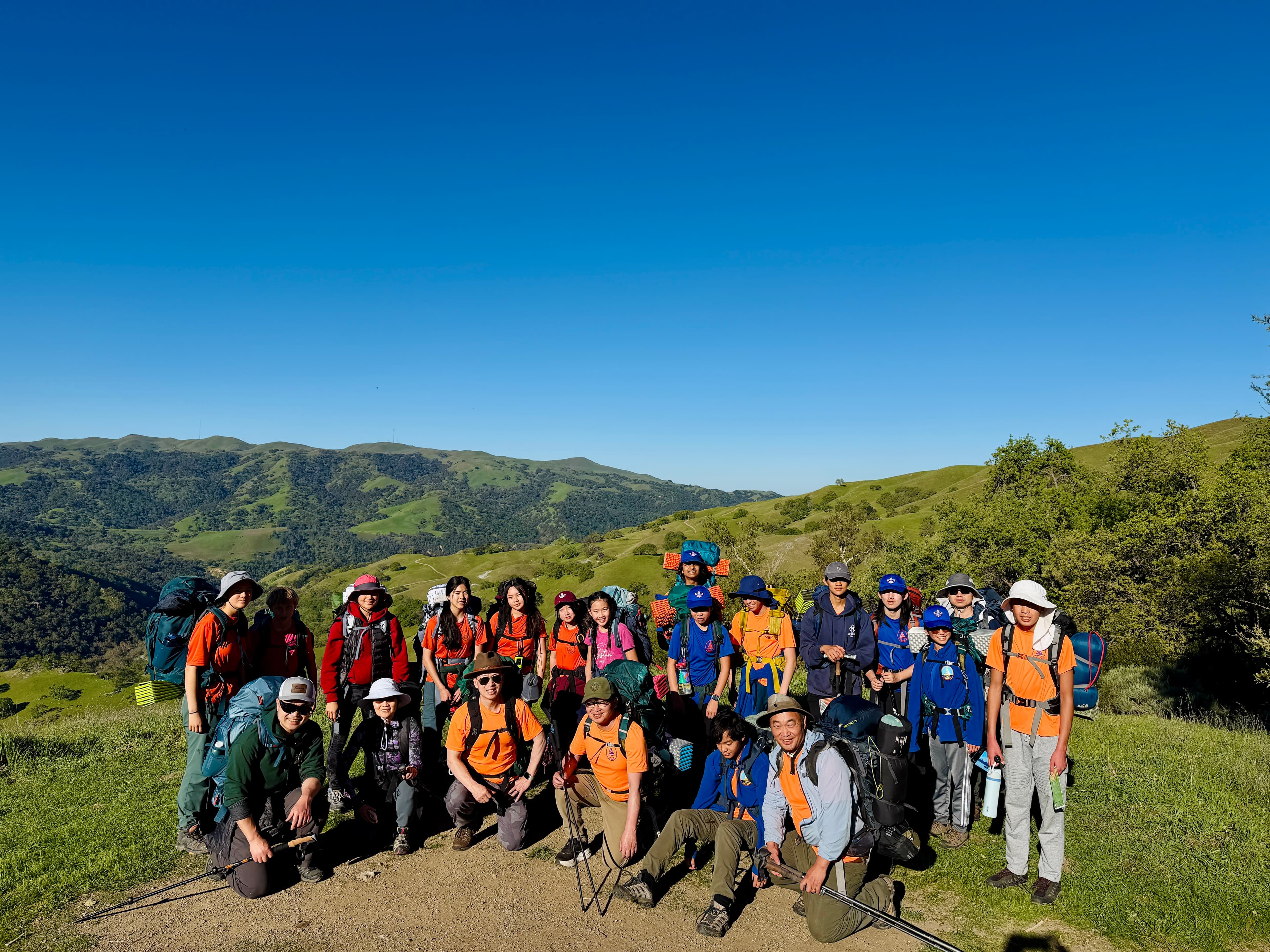 Boy and girl scouts hiking together on a sunny ridge